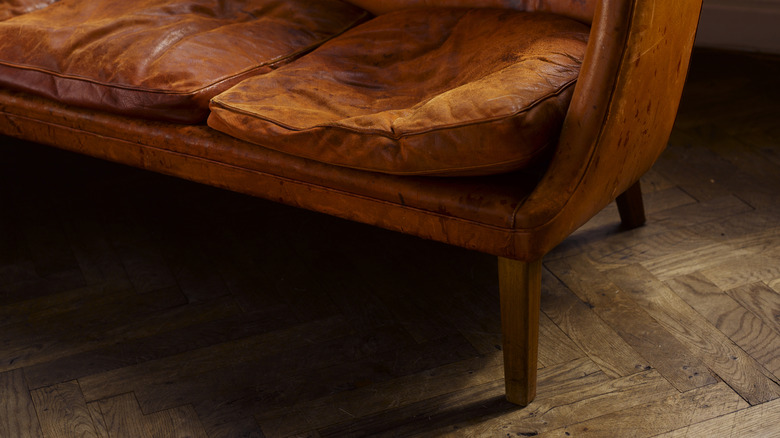 A moody shot of a sofa on warm wood parquet flooring