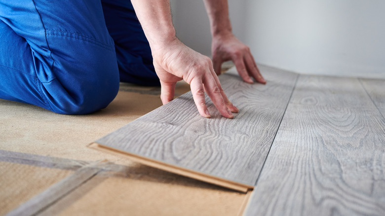Close-up of a person installing click-lock laminate wood flooring