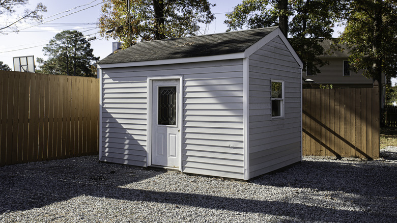 White shed on gravel in a backyard