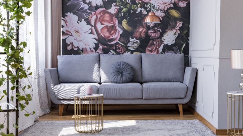A living room nook has one wallpapered accent wall with a large, moody floral print.