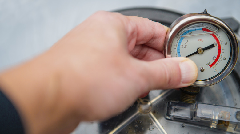 Person measuring water pressure on an outdoor faucet