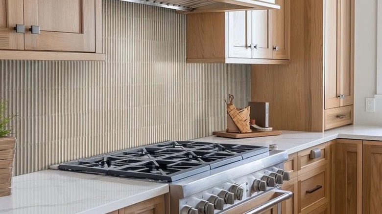 neutral fluted tile backsplash behind stove top in kitchen
