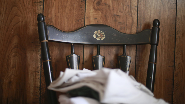 An antique black chair against dark wood paneling