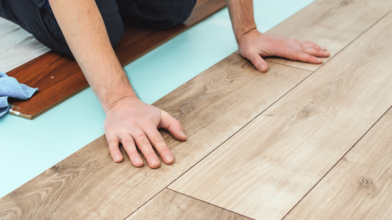 person installing hardwood floating floorboards