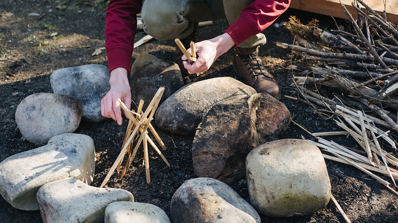 Person building a fire in a rock fire ring