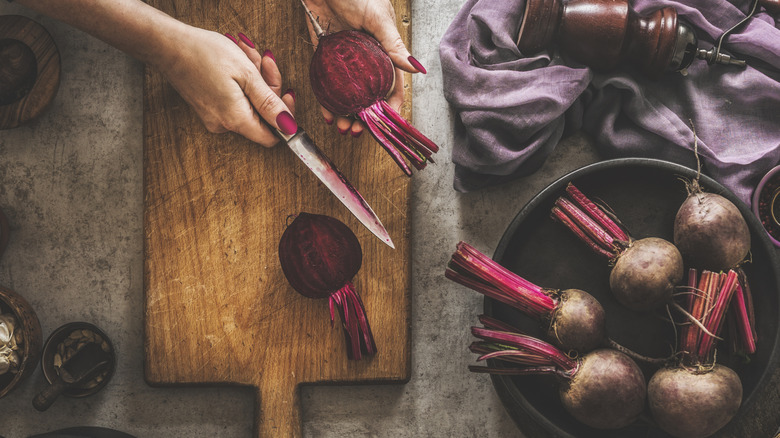 person cutting fresh beets on cutting board