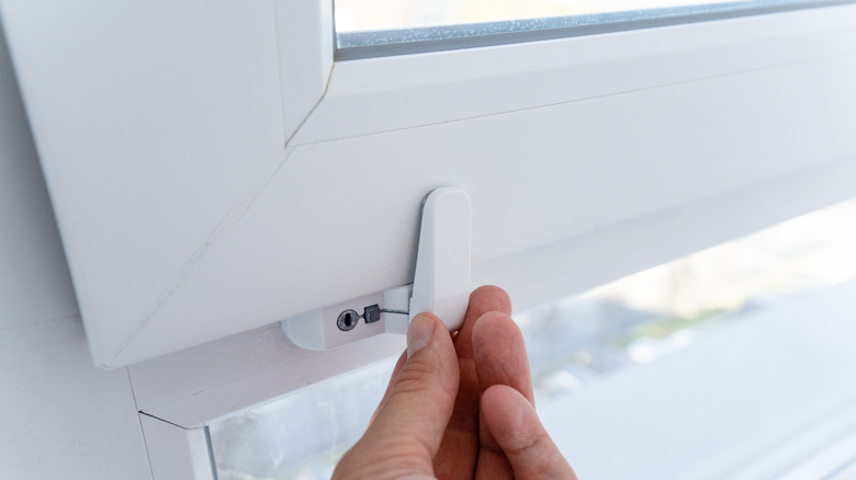 person securing latch-style lock on window