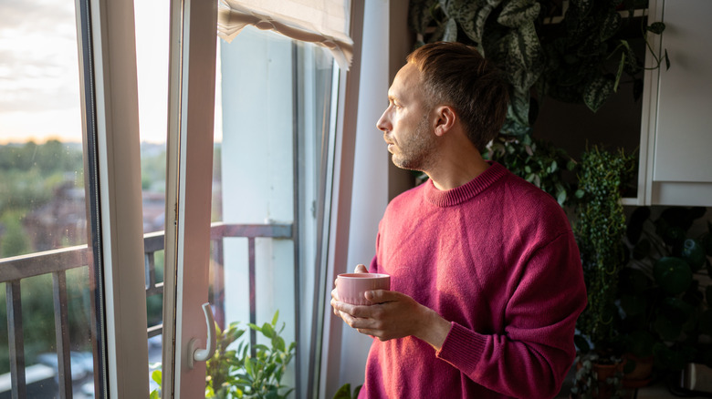 man looking out of open window