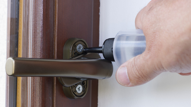 person lubricating indoor window mechanics