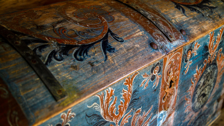 An antique chest painted with rosemailing details