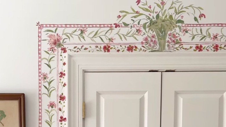 A white door with a hand-painted pink and green floral border