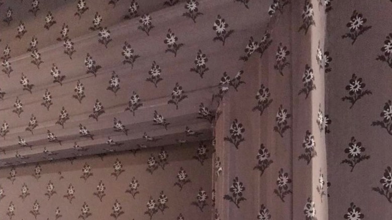 A doorframe, door, and wall covered in the same purple floral wallpaper