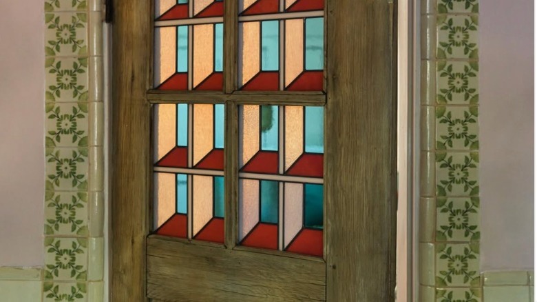 A wood door with geometric stained glass panels