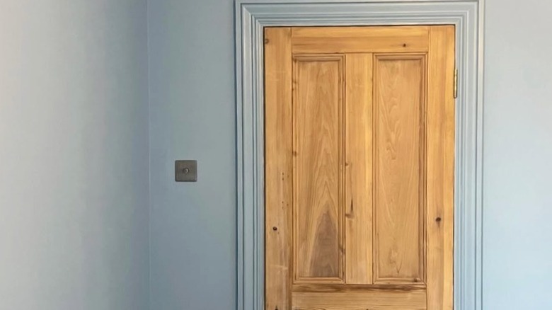 A natural pine wood door in a room painted light blue