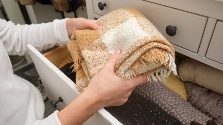 Person placing blanket into a drawer