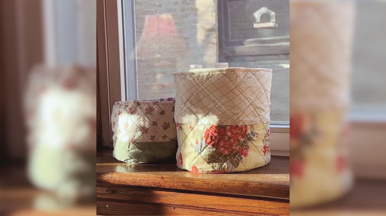 Two DIY Anthropologie-inspired fabric bins sit in a windowsill in a home.