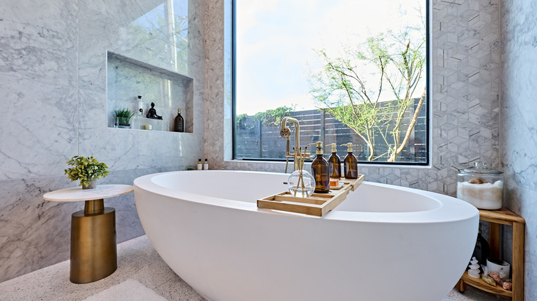 A luxurious bathroom with a free-standing tub right in front of a large window