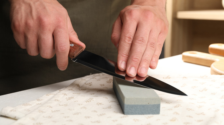 Person sharpening a knife on a whetstone