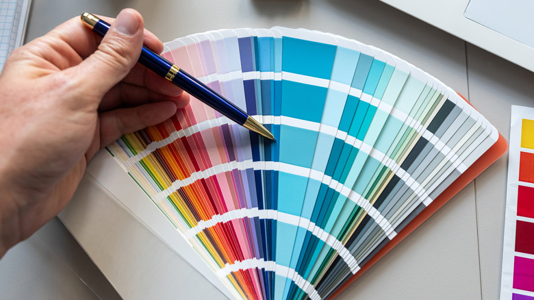 Pen pointing to dark blue shade in paint swatch with many colors