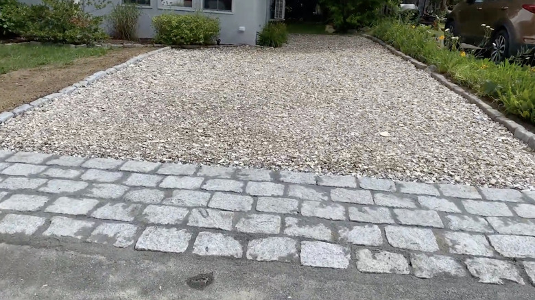 A crushed shell driveway with cobblestones separating it from the road
