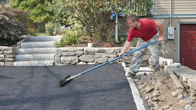 A person smoothing asphalt on a new driveway