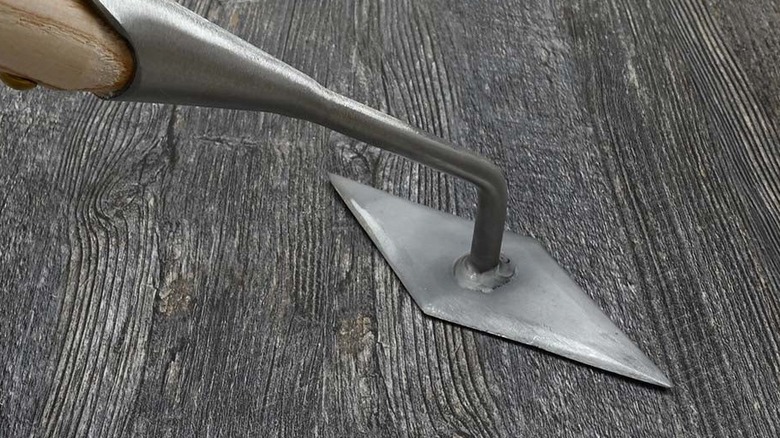 Diamond hoe head against a gray wooden background