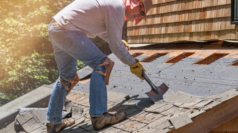 a man removing shingles from a roof