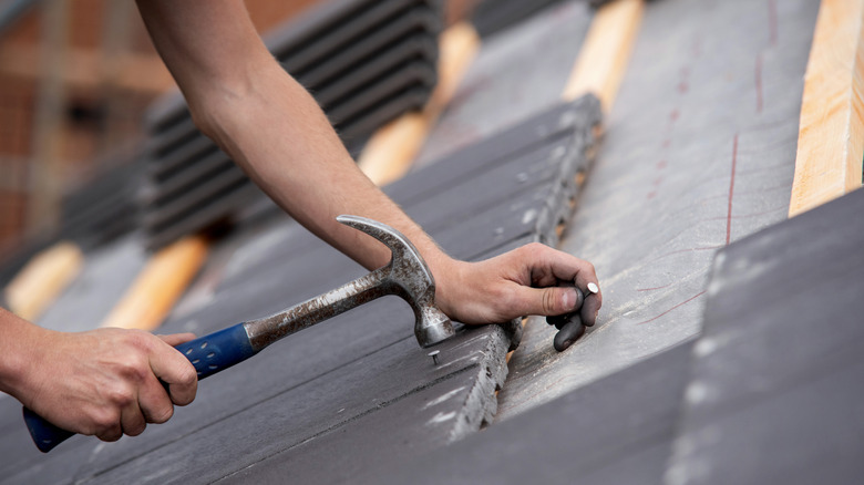 a roofer installs concrete tiles on a roof