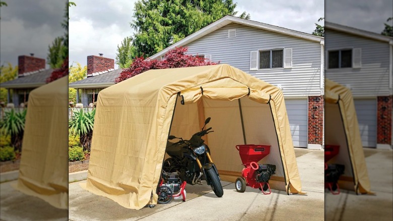 A portable shed positioned in front of a house and used to store a motorcycle and lawn equipment.