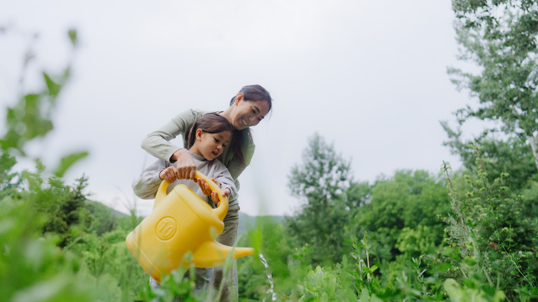 Photo of a mother and daughter gardening together in beautiful nature, smiling and enjoying themselves