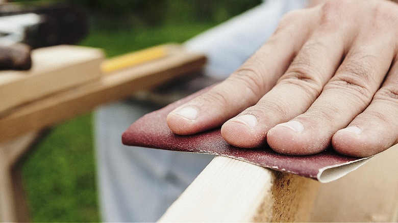 Close-up of a person sanding a piece of wood by hand