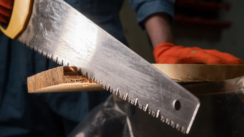 A man cutting through a piece of wood with a hand saw
