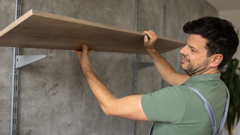 Man installing shelves on wall in a garage