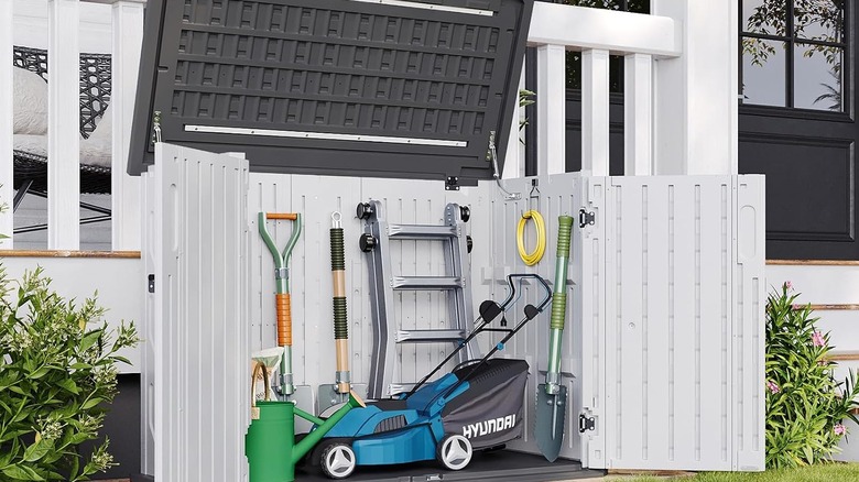 The Aoxun Storage Cabinet from Amazon being used to store a lawn mower and supplies