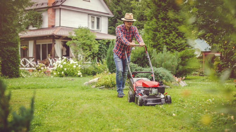 a man mowing his lawn near his house