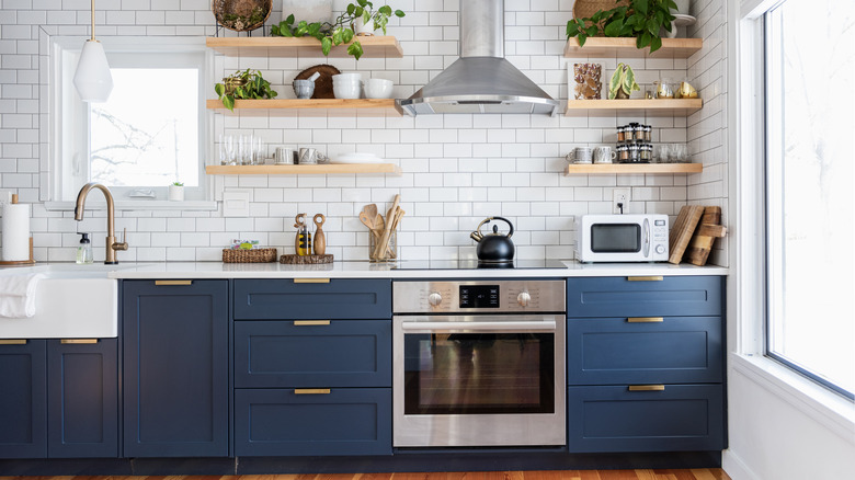 A white and blue kitchen with focus on kitchen range and stovetop