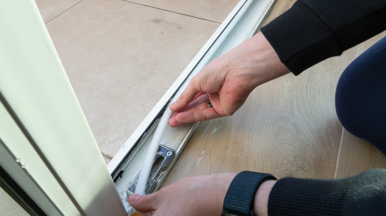 person installing weather stripping tape