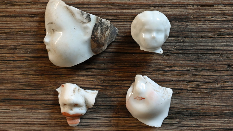 A series of cracked doll heads on a table.