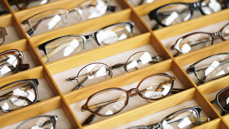 A series of eyeglasses in a wooden box with a soft cream bottom