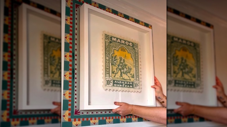 A colorful geometric frame is painted on a wall around a piece of art.