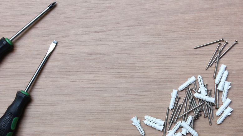 Nails, wall anchors, and screwdrivers on a table