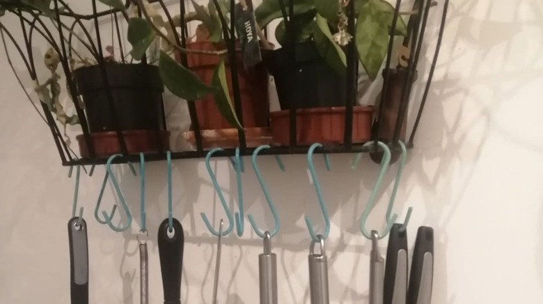 a metal planter holding potted plants above and utensils below