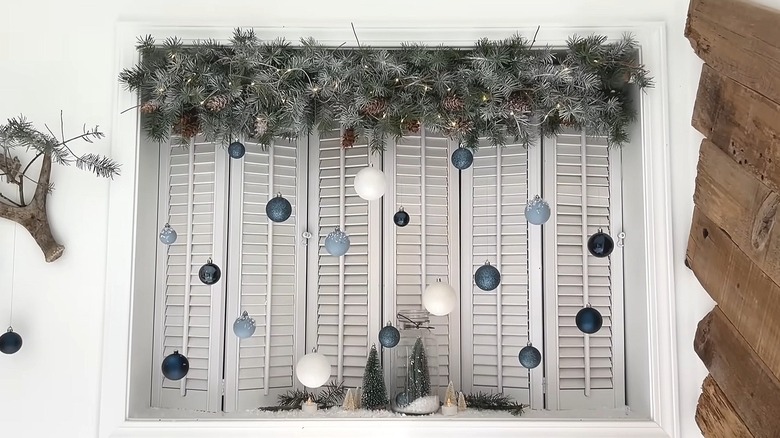 Pine bough window topper using a pool noodle as the base with ornaments hanging off of it