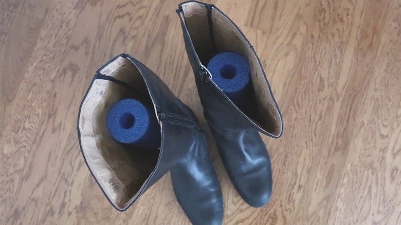 Tall black fashion boots with blue pool noodles in them to hold them upright