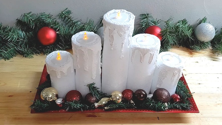 Oversized candles made from pool noodles and battery-powered tea lights on a tray with holiday accents