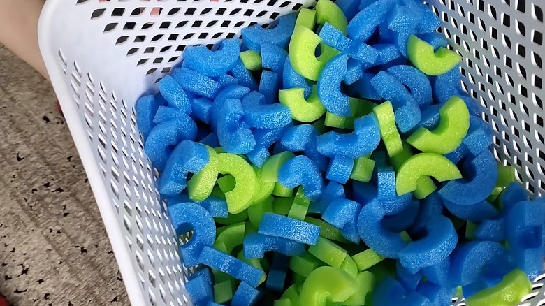 White bin of blue and green pool noodles cut into small pieces to serve as packing protection