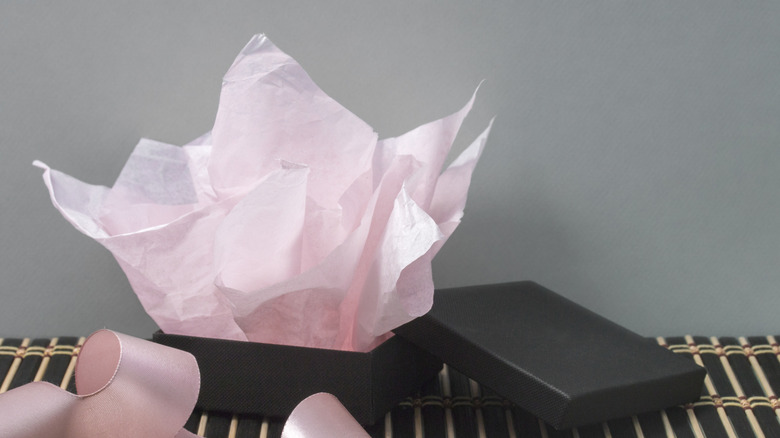An open, unwrapped gift box with pink tissue paper.