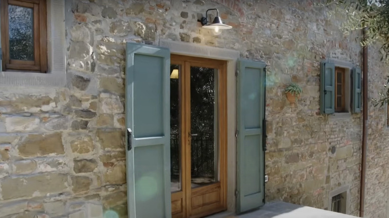 An Italian stone house with green shutters.