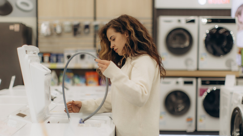 A woman looking at washing machine options at an appliance store