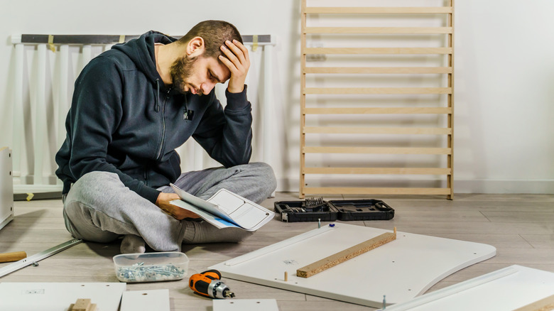 Frustrated man trying to assemble furniture